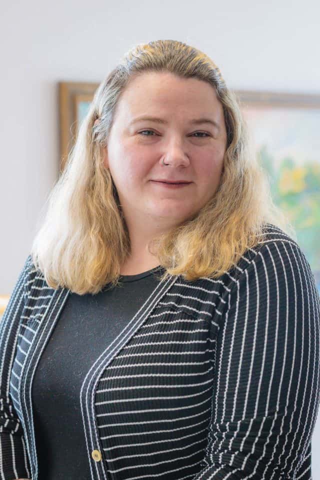 Headshot of a white woman with blond hair wearing a striped black and white suit jacket