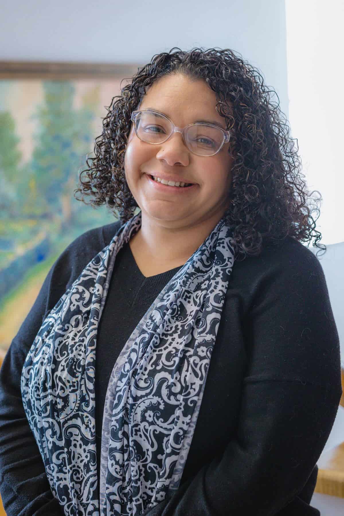 Latine woman wearing a black jacket and a scarf